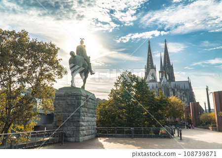 View of Cologne Cathedral and the equestrian statue of Kaiser Wilhelm II against the background of the sun and cloudy sky View of Cologne Cathedral and the equestrian statue of Kaiser Wilhelm II against the background of the sun and cloudy sky 108739871