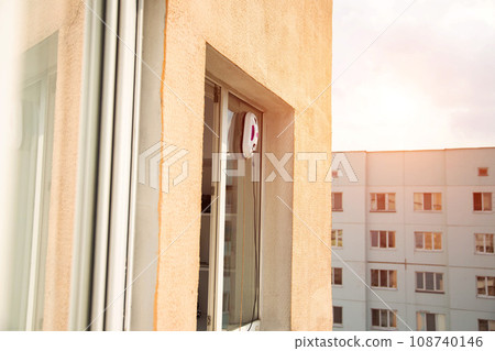 A modern vacuum robot window washer washes glass in an apartment on a balcony. View outside from the street. Safety from falls from a height. A modern vacuum robot window washer washes glass in an apartment on a balcony. View outside from the street. Safety from falls from a height. 108740146