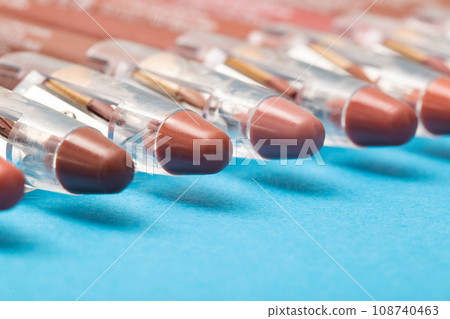 Set of brown soft lip pencils on a blue background. Concept of trendy makeup cosmetics for a girl, close-up. Copy space for text Set of brown soft lip pencils on a blue background. Concept of trendy makeup cosmetics for a girl, close-up. Copy space for text 108740463