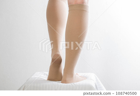 Female legs in compression stockings for varicose veins on the legs. White background. Circulation in the legs. thrombosis in the veins, lymphedema. Chronic venous insufficiency Female legs in compression stockings for varicose veins on the legs. White background. Circulation in the legs. thrombosis in the veins, lymphedema. Chronic venous insufficiency 108740500