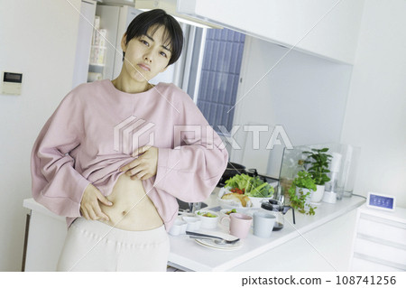 一位年輕女子在廚房前擔心腹部脂肪 108741256