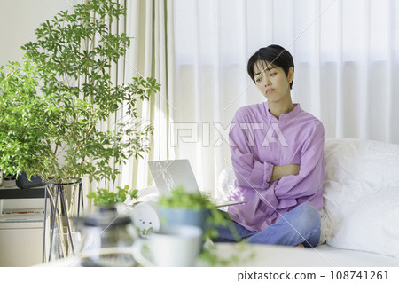 A dissatisfied young woman sitting cross-legged on the bed with her arms crossed A dissatisfied young woman sitting cross-legged on the bed with her arms crossed 108741261
