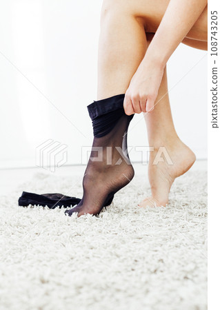a woman puts on her legs tights slender legs black tights 108743205