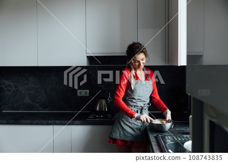 housewife prepares food in the kitchen with gloves housewife prepares food in the kitchen with gloves 108743835