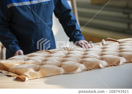 Worker's hands make furniture. Make a carriage screed on the sofa. 108743921