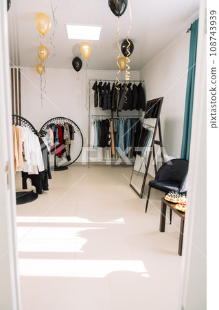 Clothes store with racks of clothes and a large mirror Clothes store with racks of clothes and a large mirror 108743939
