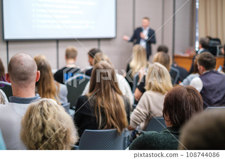 Back view of businesswoman attending presentation with diverse participants in conference hall  108744086