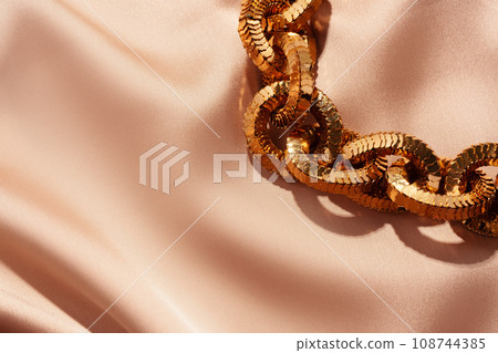 Golden chain necklace on silk background close up 108744385
