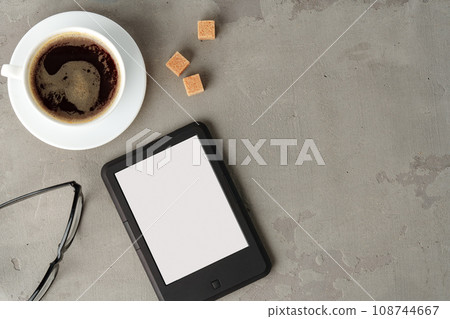E-book reader with glasses on gray background close up E-book reader with glasses on gray background close up 108744667