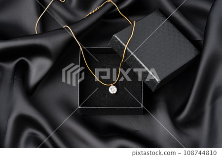 Golden necklace on silk texrtile background close up 108744810