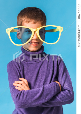 Cheerful little boy in big glasses express a surprised face isolated on blue background. Cheerful little boy in big glasses express a surprised face isolated on blue background. 108744882