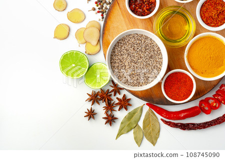Bowls with spices on wooden board on white background 108745090