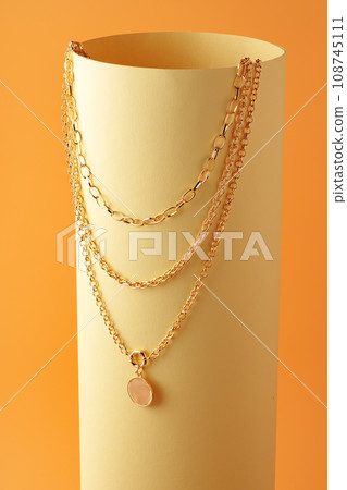 Golden chain with a pendant on yellow sheet of paper Golden chain with a pendant on yellow sheet of paper 108745111