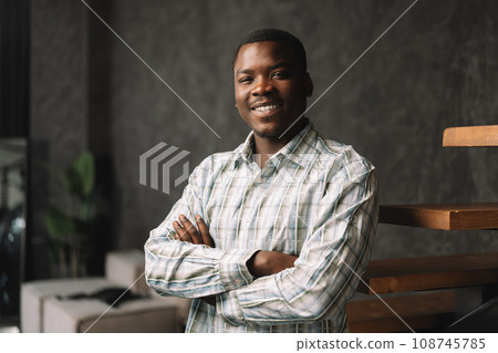 Confident young african businessman standing near wooden ladder portrait 108745785
