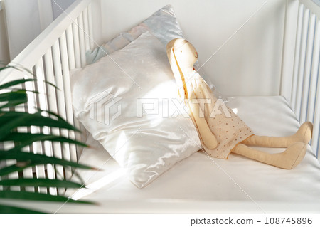 Wooden white baby crib and toy rabbit close up Wooden white baby crib and toy rabbit close up 108745896