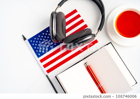 Notepad with USA flag and headphones on white background. English language audio courses educational concept 108746006