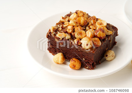 Piece of brownie cake with hazelnuts on white background Piece of brownie cake with hazelnuts on white background 108746098