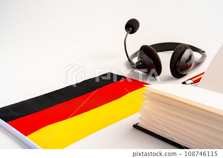Notepad with German flag and headphones on white background. German language audio courses educational concept 108746115