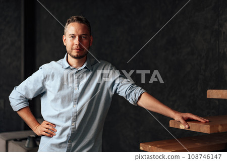 Confident young businessman standing near wooden ladder portrait Confident young businessman standing near wooden ladder portrait 108746147