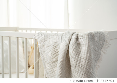 Muslin baby blanket hanging on child's bed in nursing room Muslin baby blanket hanging on child's bed in nursing room 108746203