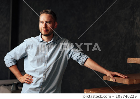 Confident young businessman standing near wooden ladder portrait Confident young businessman standing near wooden ladder portrait 108746229