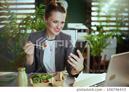 happy business owner woman in green office eating salad happy business owner woman in green office eating salad 108746433
