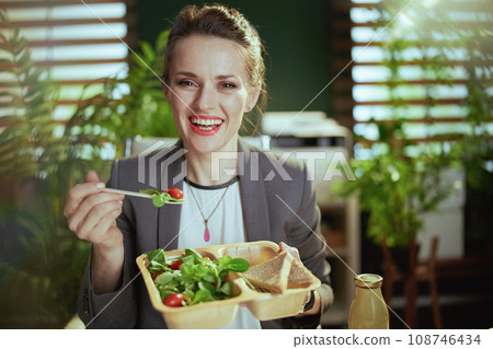 happy business owner woman in green office eating salad happy business owner woman in green office eating salad 108746434