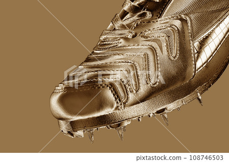Fragment of a gold sneaker with spikes on a gold background 108746503