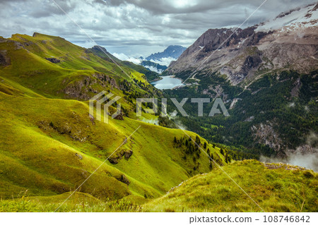 landscape with mountains, hills, Fedaia lake, clouds and forest 108746842