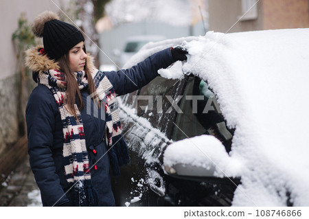Woman clean car after night snowfall. Preparing to drive at work 108746866