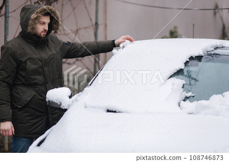 Man clean car from snow by hands after night snowfall Man clean car from snow by hands after night snowfall 108746873