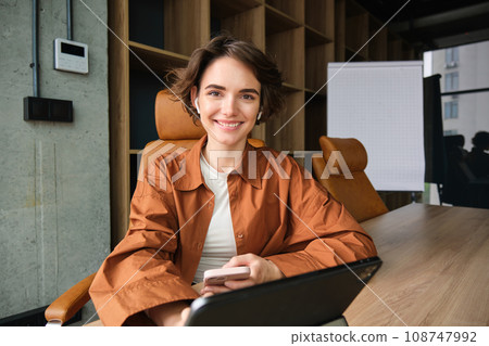 Portrait of female employee, start up entrepreneur in office, working with digital tablet, sitting in conference room waiting for team meeting Portrait of female employee, start up entrepreneur in office, working with digital tablet, sitting in conference room waiting for team meeting 108747992
