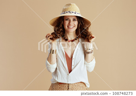 smiling woman in blouse and shorts on beige 108748273