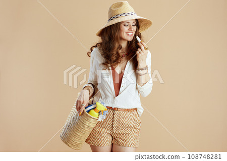happy stylish woman in blouse and shorts isolated on beige 108748281