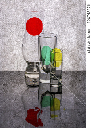 Still life with glass objects with colored spots on a reflective surface 108748376