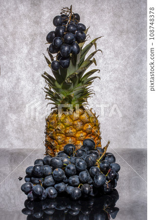 Still life with pineapple and bunches of ripe grapes 108748378