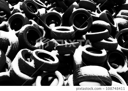 Pile of old tyres covered by snow. Black and white photography. 108748411