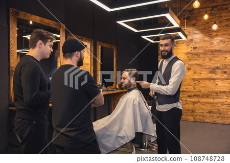 Barber teaches student to make men's hairstyles on model. Barber teaches student to make men's hairstyles on model. 108748728
