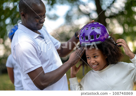 Dad fixing a protective hemlet on his kids head Dad fixing a protective hemlet on his kids head 108748869