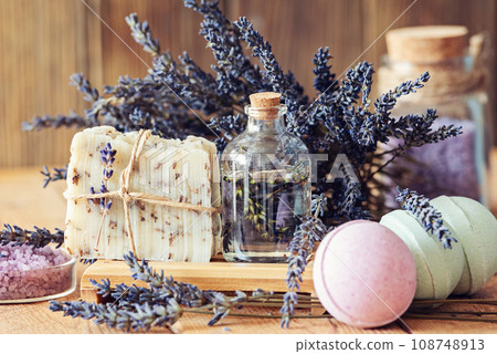 Wellness treatments with lavender flowers on wooden table. Spa still-life. Essential oils, sea salt, towels and handmade soap. Natural herb cosmetic with lavender flowers 108748913