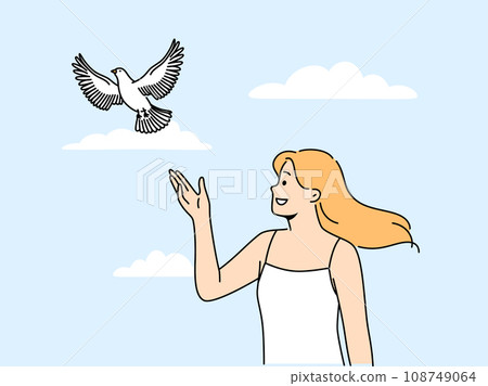 Woman releases dove standing under summer blue sky and watching bird symbolize hope and peace 108749064