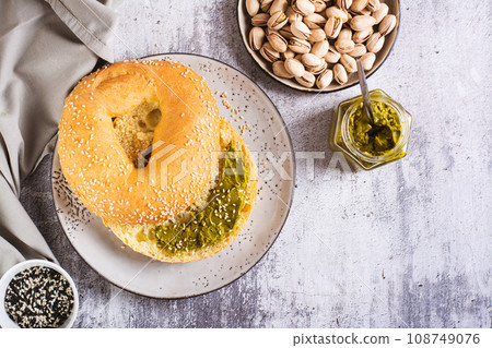 Bagel with pistachio cream butter for breakfast on a plate on the table top view 108749076