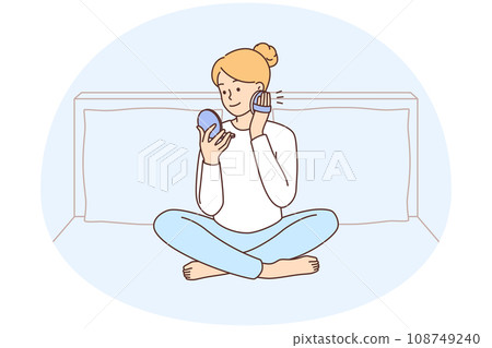 Woman sitting on bed doing makeup 108749240