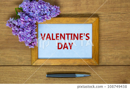 February 14 valentines day symbol. Wooden frame with words 'Valentines day'. Lilac branch and metalic pen. Beautiful wooden background, copy space. Happy Valentines day concept. 108749438