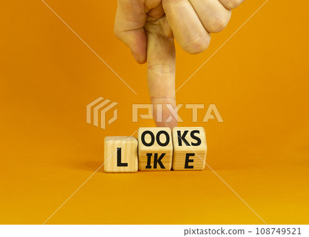 Looks like symbol. Concept words Looks like on wooden cubes. Businessman hand. Beautiful orange table orange background. Business, popular quotes and looks like concept. Copy space. 108749521