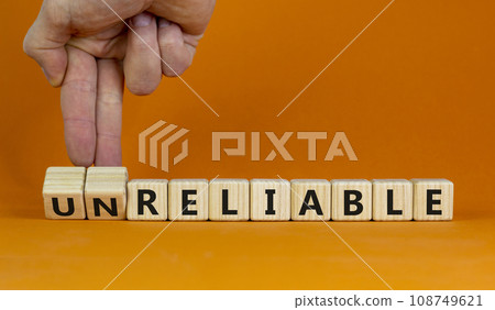 Unreliable or reliable symbol. Businessman turns wooden cubes and changes the word unreliable to reliable. Beautiful orange background, copy space. Business and unreliable or reliable concept. 108749621