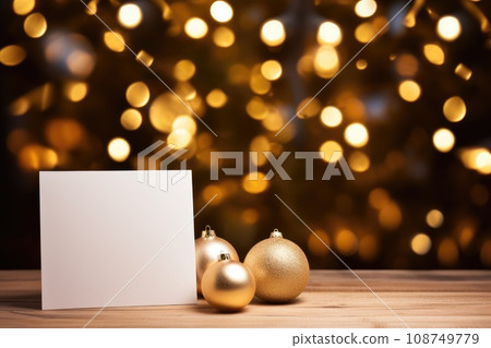 Blank Christmas card next to golden Christmas ornaments on wooden table Blank Christmas card next to golden Christmas ornaments on wooden table 108749779