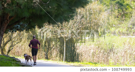 A man running in park with dog- autumn 108749993
