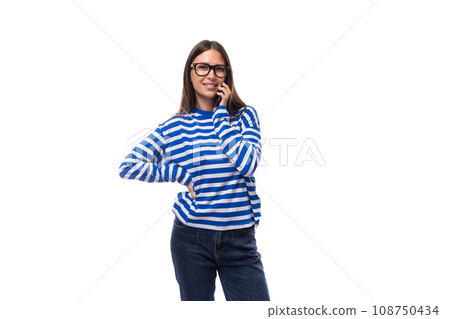 young cute brunette lady in a blue striped casual blouse speaks on the phone 108750434