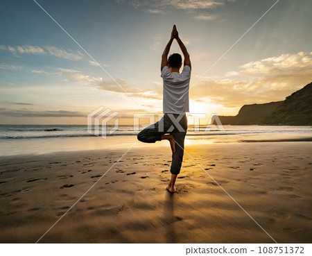 Woman doing yoga on the sandy beach at sunset 108751372